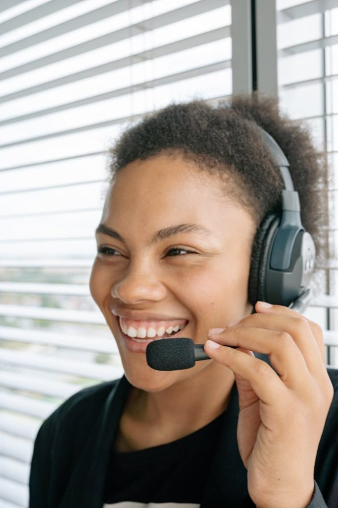 Happy woman working in customer support wearing a headset, smiling while speaking.